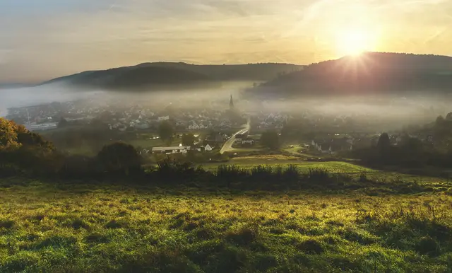 A village in a misty valley at sunrise